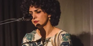 Female singer in a floral dress, eyes closed mid-song at the Nowruz Festival, Sargfabrik Vienna, March 2018.